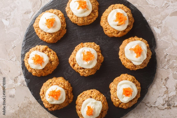 Fototapeta Soft crumbly carrot oatmeal cookie cake with cream cheese frosting close-up on plate on table. Horizontal top view from above