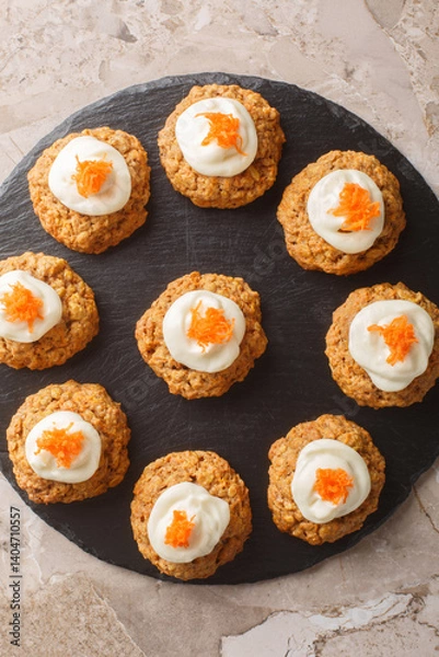 Fototapeta Delicious carrot cake cookies with cream cheese frosting are a must-have Easter dessert close up on the plate on the table. Vertical top view from above