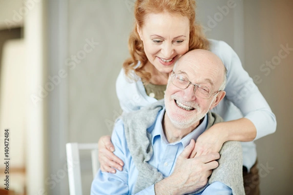 Fototapeta  Portrait of elderly gray haired man embracing his wife and smiling enjoying quiet retirement days at home