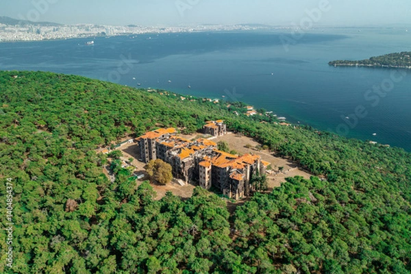Fototapeta Buyukada Greek Orphanage. Aerial view of the Buyukada Greek Orphanage on a coastal hill surrounded by lush vegetation with the sea in the background. Istanbul, Turkey.
