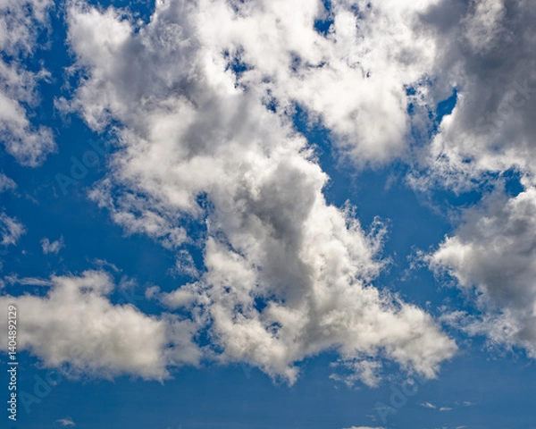 Obraz Bright blue sky filled with fluffy clouds during a sunny day in springtime.