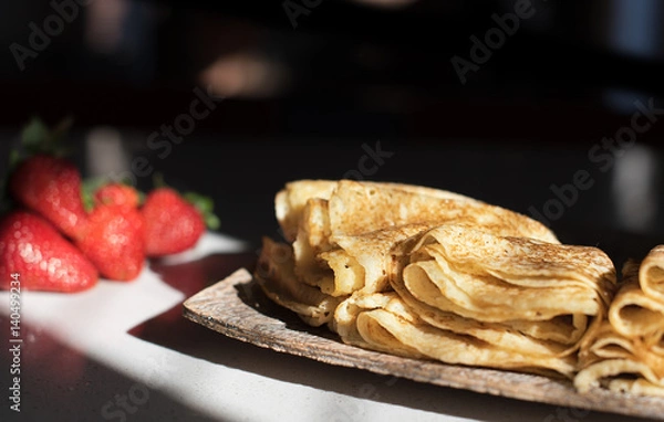 Obraz Pancakes on the wooden plate stay on the table with sunlight from window on them