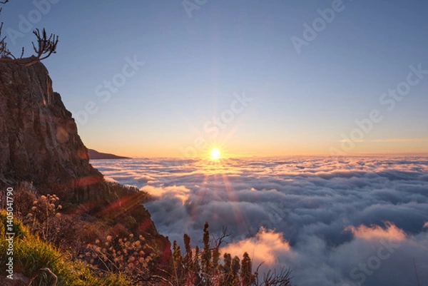 Fototapeta Breathtaking sunrise view over a sea of clouds in Teide National Park, Tenerife, Canary Islands. The silhouette of Mount Teide, Spain's highest volcano, rises in the background as morning light floods