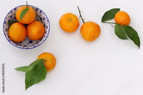 Obraz Top view of a fresh mandarin orange fruits with leaves on a white background. Ripe orange tangerine citruses frame. Photo from above.