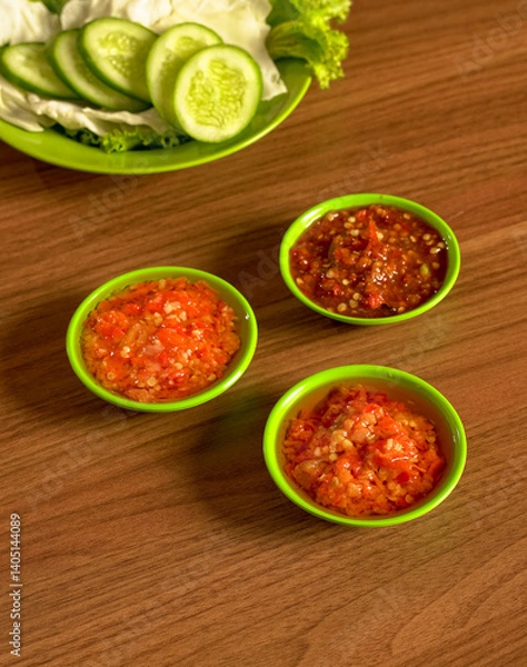 Fototapeta Three Kinds Of Indonesian Chili Sambals With Cucumber Slices, Cabbage, And Lettuce As Classic Sundanese Side Dish.