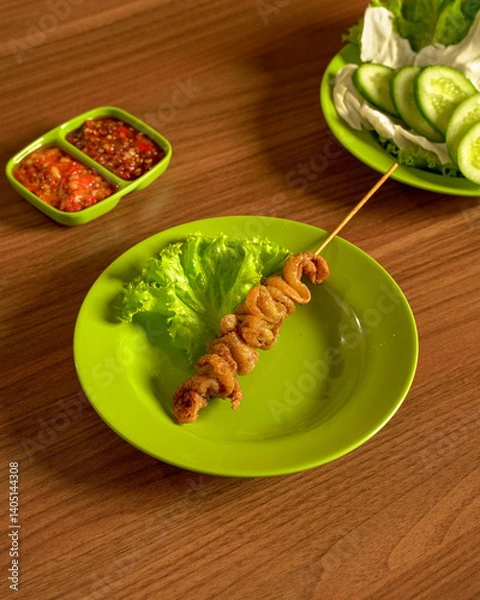 Fototapeta Delicious Chicken Skin Satay with Fresh Raw Vegetables and Spicy Sambal, Indonesian Street Food Served with Flavorful Traditional Sides.