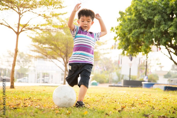 Fototapeta Boy learning kick ball at the park in the evening