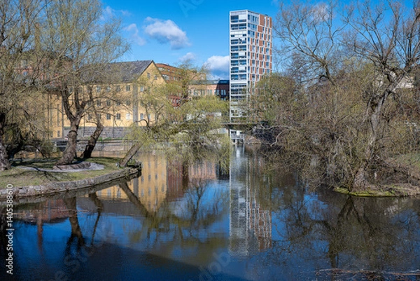 Fototapeta Motala Stream and the industrial landscape at Gamlebro during early spring 2025 in Norrköping. Norrköping is a historic industrial town in Sweden.