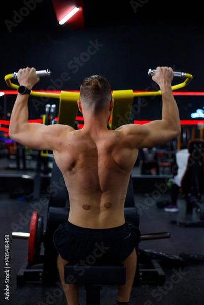 Obraz Caucasian guy doing lat pulldowns on a machine in the gym
