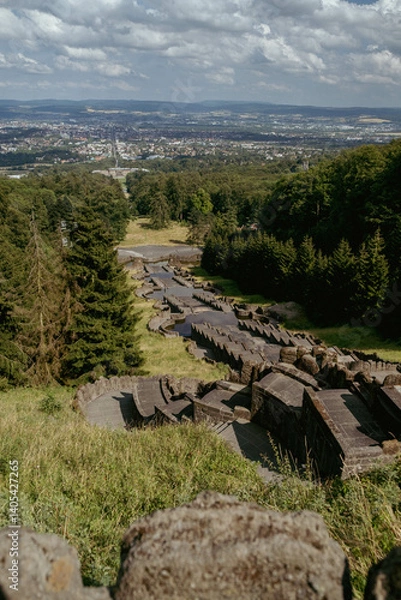 Fototapeta Panoramic view of a Kassel city with a stone structure in the foreground, under a bright sky with scattered clouds.