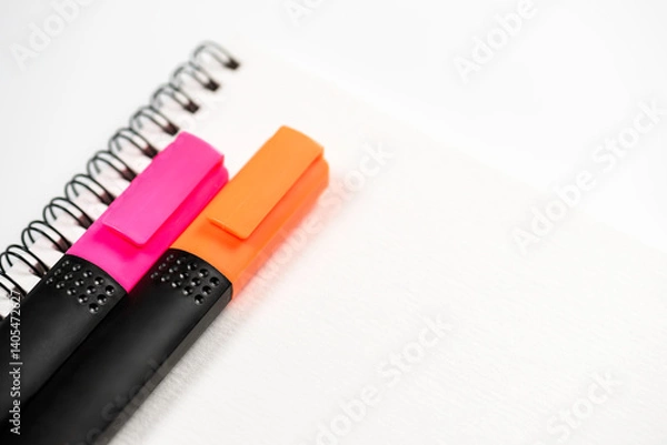 Obraz Two markers lie on notebook with spiral on white background.