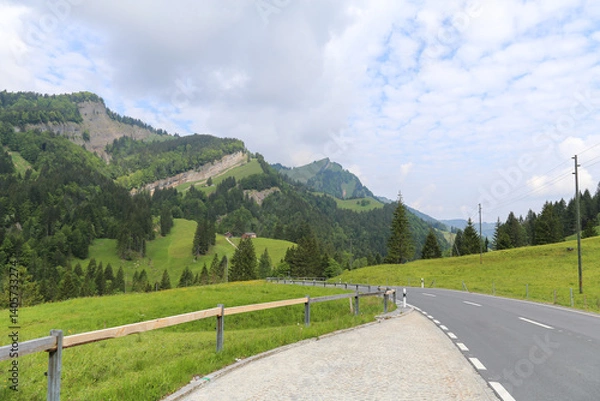 Obraz A road with a fence on the side and a mountain in the background in Switzerland