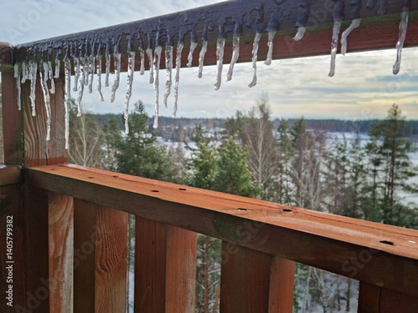 Obraz View of a snowy panorama on a sunny day from a wooden balcony. Melting icicles hanging on a wooden deck. Season changing.