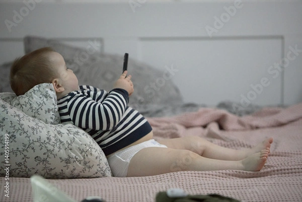 Fototapeta Toddler boy using phone on bed