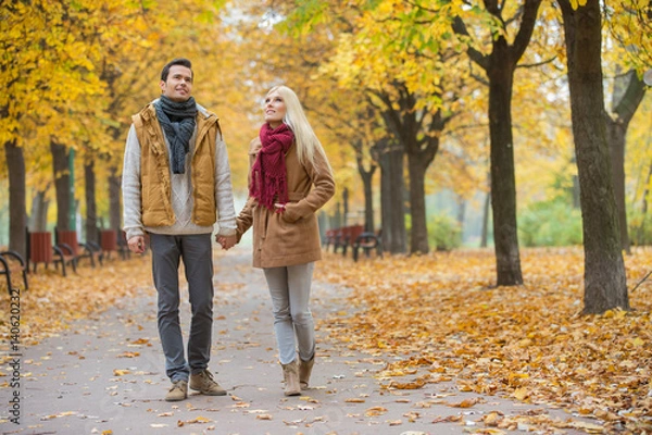 Fototapeta Full length of couple walking while looking up in park during autumn
