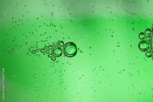 Fototapeta Abstract background from bubbles of carbonated water through a green glass bottle, art image, macro