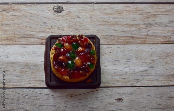 Fototapeta Top views of Fruit cake placed on a dark brown plastic tray on a wooden table background at Thailand, selective focus.