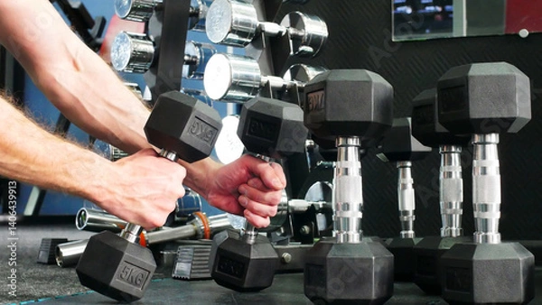 Fototapeta Close-up of many different barbells in a gym and a man taking two