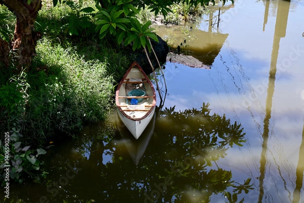 Fototapeta Closeup of A white canoe is on the bank of a canal in the garden with natural background at Thailand.