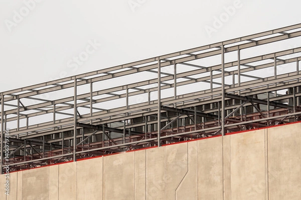 Fototapeta concrete building and metal beam frame during construction against grey sky
