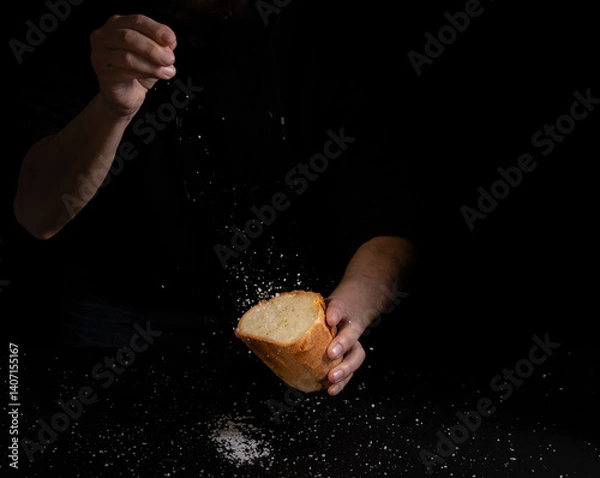 Obraz Salting bread on black background, concept