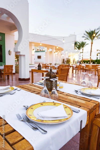 Fototapeta Relaxing outdoor dining setup at a coastal restaurant with elegant table settings in the evening