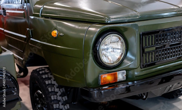 Fototapeta Close-up of round headlights of a green military vehicle. Historical vehicle. Round headlight of a green vintage military vehicle.