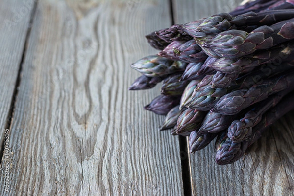 Obraz Fresh bunch of purple asparagus on dark wooden background. Healthy food concept. The vegetable is rich in fiber, a natural prebiotic.