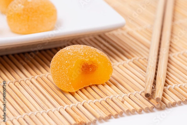 Fototapeta Sweet Mango Flavored Fruit Mochi on a Bamboo Mat with Chopsticks