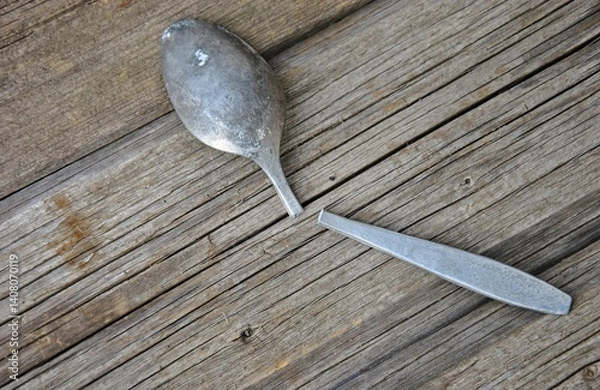Fototapeta old broken spoon on a wooden table. top view