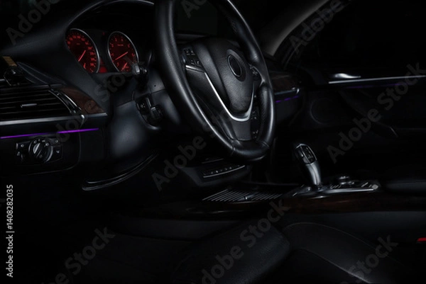 Fototapeta Close-up view of a car's dashboard at night with illuminated controls and a black background.