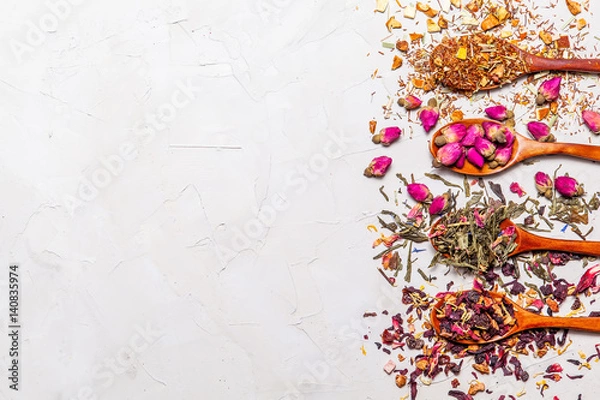 Fototapeta Dry tea in wooden spoons on grey background, top view. Leaves of red, fruit , green and black tea with  fruits and spices