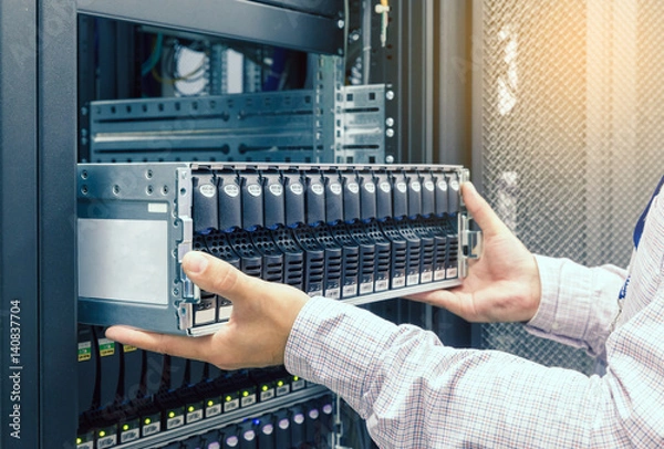 Fototapeta IT Engineer installs JBOD  to rack in datacenter