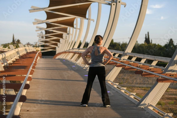 Obraz Active middle-aged woman doing stretching and jogging outdoors at sunset