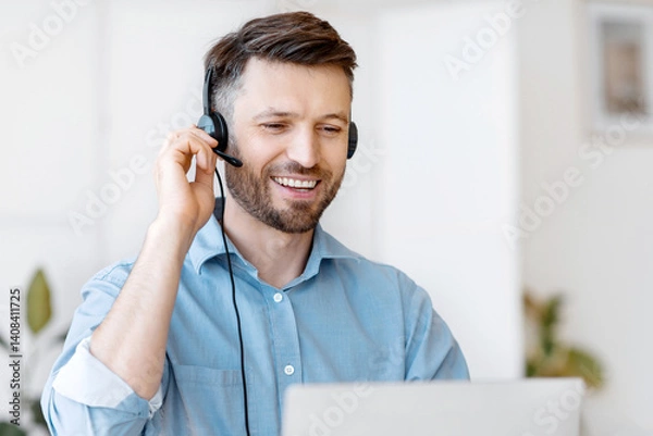 Fototapeta Hotline Operator. Handsome Young Man Customer Support Manager In Headset Working With Laptop Computer In Office, Consulting Clients Online, Managing Issues, Sitting At Desk, Free Space