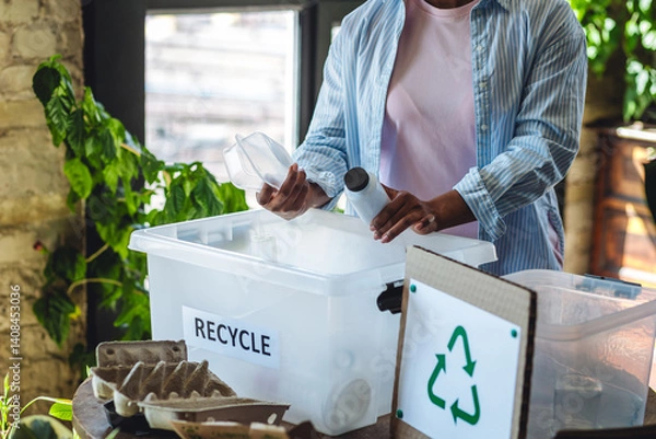 Obraz Young African American woman is doing garbage waste sorting at home. Concept of sustainable lifestyle, daily routine to protect planet from pollution, domestic life, simple actions for environment