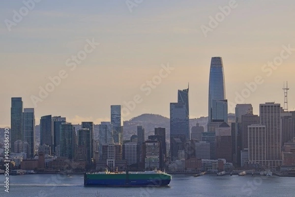 Fototapeta The sun sinks lower in the sky, casting shadows on the skyline of San Francisco