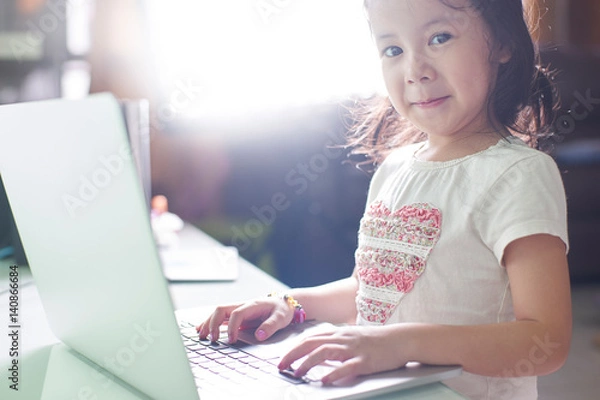 Fototapeta Little asian girl enjoy using laptop to studying .