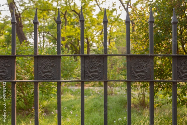 Fototapeta Black forged fence decorated with images of dragons