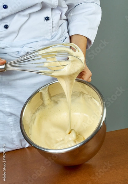 Fototapeta chef whips yellow cream in a bowl by hand for making cheesecakes