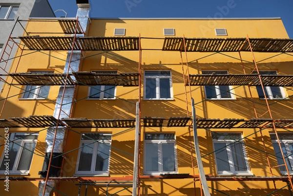 Fototapeta Building facade renovation, scaffolding. Extensive scaffolding providing platforms for work during renovation in a multi-story building