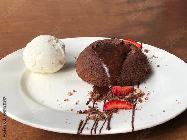 Obraz Chocolate Lava Cake with Melting Center and Vanilla Ice Cream, Served on White Plate with Wooden Background