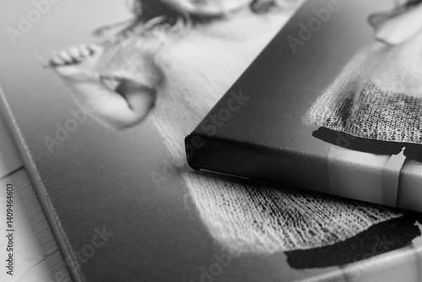 Fototapeta Detailed close-up of black and white canvas prints featuring a joyful child, stretched on wooden stretcher bars with gallery wrapping. Textured surface and sharp edges visible