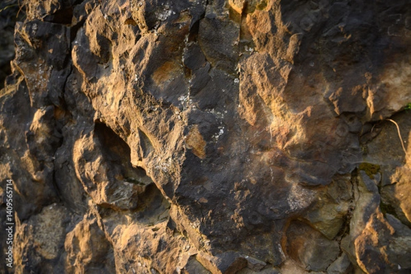 Fototapeta Natural rock texture in warm sunlight with detailed rough surface and natural shadow play. Ideal for design backgrounds, geology themes, and architecture textures.