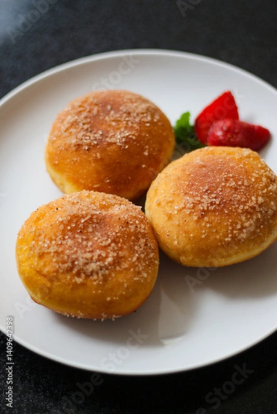 Fototapeta A handmade bombolone or bomboloni is an Italian-filled doughnut that is eaten as a snack or dessert. Selective focus.