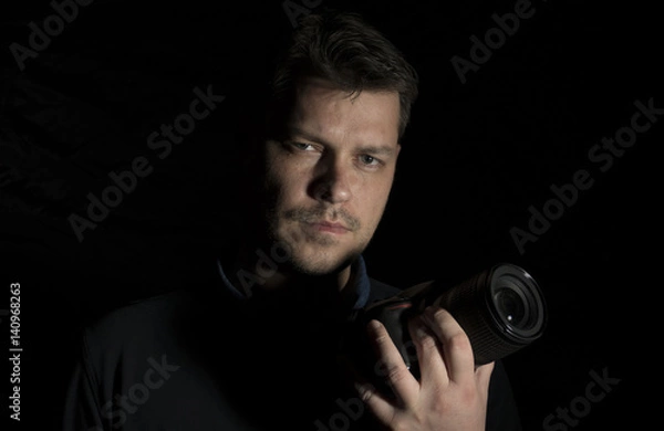 Fototapeta Young man as a photographer portrait isolated on black background