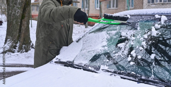 Fototapeta a man removes snow from a car. Scraping ice.