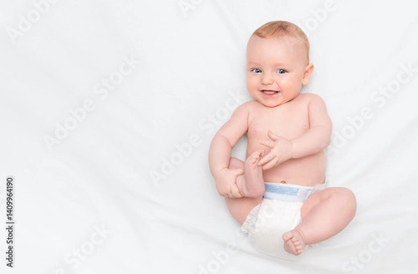 Fototapeta Five month old baby lying on his back, smiling and holding his leg