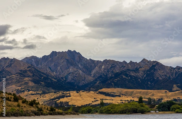 Fototapeta Lake Wanaka, a summer cloudy afternoon with a mountain range and the town of Wanaka on the shore. South Island, New Zealand