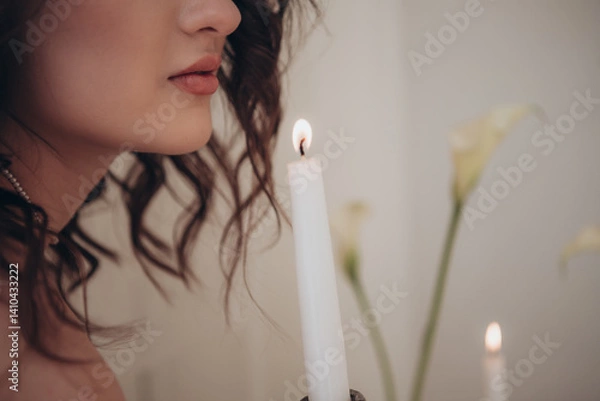 Fototapeta Romantic close-up of a woman’s face, candle flame and soft floral background